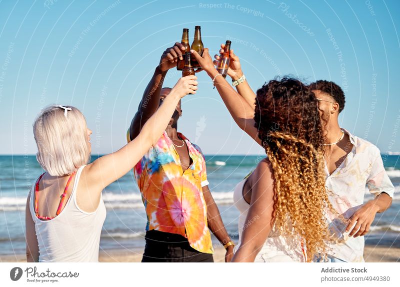 Fröhliche multiethnische Freunde stoßen bei einem Sommerfest mit Bierflaschen an Menschen Zuprosten Lächeln Zusammensein trinken Glück Klirren Treffpunkt Anlass