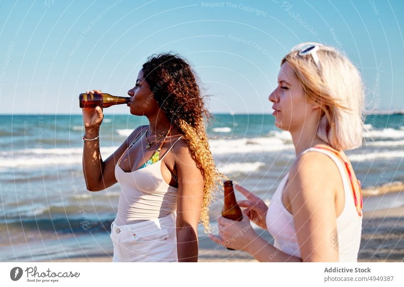 Junge Frauen stehen am Meer und trinken Bier an einem Sommertag Strand MEER Meeresufer Freund Feiertag Zeit verbringen bewundern Zusammensein Ufer jung