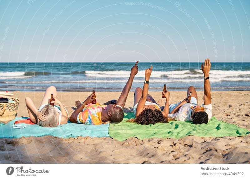 Junge diverse beste Freunde liegen am Meer und trinken Bier Menschen Lügen Strand Urlaub sich[Akk] entspannen nach oben zeigen Feiertag Zeit verbringen