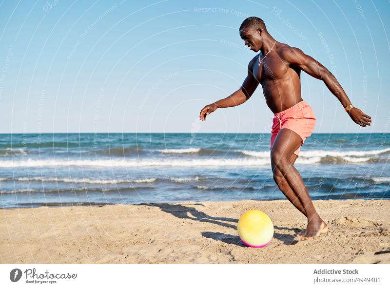 Schwarzer Mann kickt Ball am Strand Kick MEER spielen Lächeln Spaß haben Energie Sommer männlich schwarz Afroamerikaner ethnisch Glück Sand ohne Hemd Urlaub