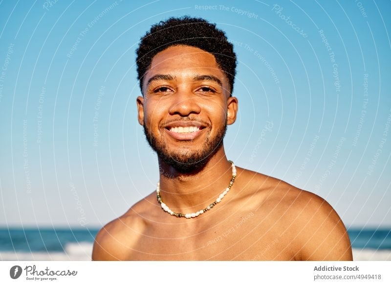 Afroamerikanischer Mann steht auf dem Meer Lächeln MEER Strand winken Wochenende Porträt Tourist männlich Afroamerikaner ethnisch jung Urlaub Resort Küste