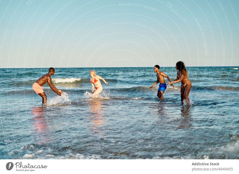 Multirassische Freunde spielen im Meerwasser Sommer MEER Wochenende Wasser platschen Strand Zusammensein winken Männer Frauen vielfältig rassenübergreifend