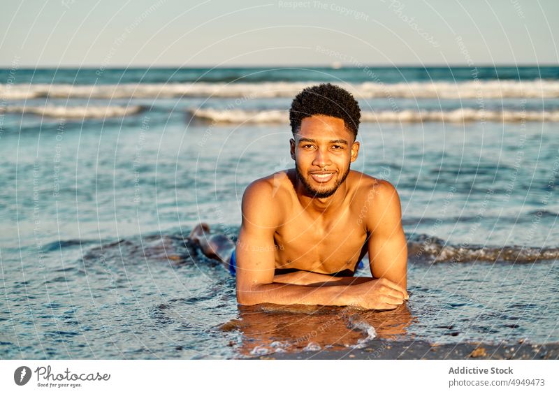 Afroamerikanischer Mann am Meer liegend Strand MEER winken Sommer Wochenende Sand Tourist nass Wasser männlich Küste Urlaub Feiertag Ufer tagsüber ohne Hemd