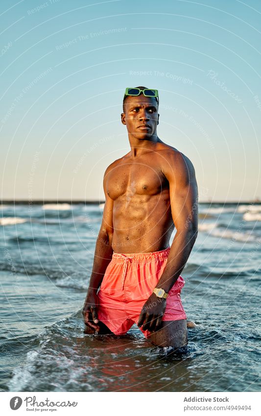 Nachdenklicher schwarzer Mann ohne Hemd im Meerwasser MEER Wasser Wochenende Sommer ausrichten Sonnenbrille Urlaub Sauberkeit stehen männlich muskulös jung
