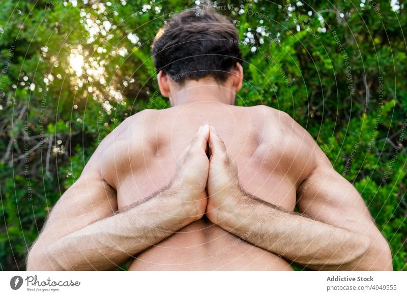 Anonymer Mann, der die Hände hinter dem Rücken verschränkt Yoga Sitzung Hände gefaltet meditieren Buchse beweglich Dehnung Sommer Wochenende männlich Park Zen
