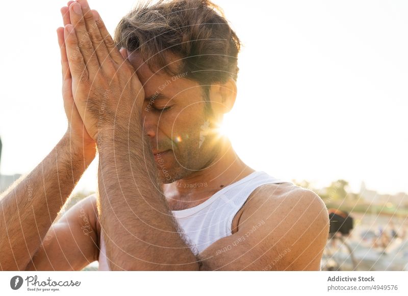 Mann mittleren Alters meditiert an einem sonnigen Morgen meditieren Sitzung Yoga Strand Chakra des dritten Auges Hände gefaltet Windstille Sonnenaufgang üben