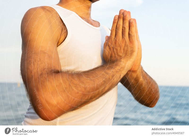 Crop männlich meditiert mit gefalteten Händen in der Nähe von Meer Mann meditieren MEER Sonnenaufgang Namaste Morgen Sitzung Yoga üben Achtsamkeit Tanktop