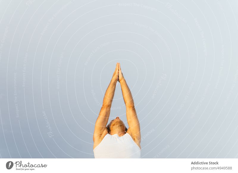 Ausgeschnittenes Männchen in Vriksasana-Pose vor grauem Himmel Mann Yoga üben Gleichgewicht Baumhaltung Sommer Zen männlich tagsüber Wohlbefinden Energie