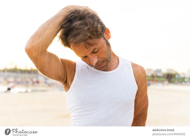 Mann mittleren Alters streckt seinen Hals am Strand Dehnung Aufwärmen Training früh Sommer Wegbiegung Übung männlich reif Lebensmitte Tastkopf Morgen