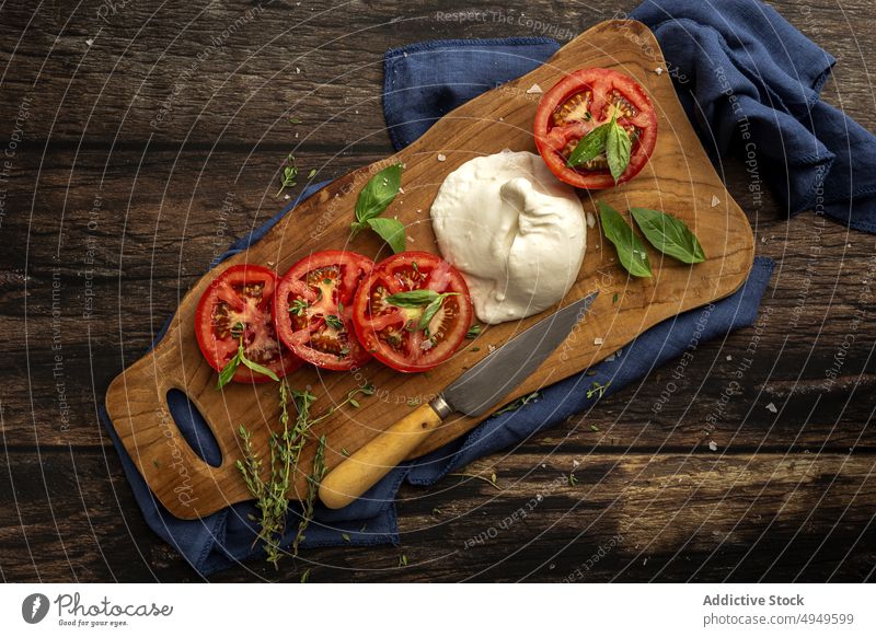 Appetitliche frische Tomate und Mozzarella mit Kräutern auf Holzbrett Schneidebrett Kraut Basilikum gesunde Ernährung Lebensmittel Käse Gemüse Mahlzeit Thymian