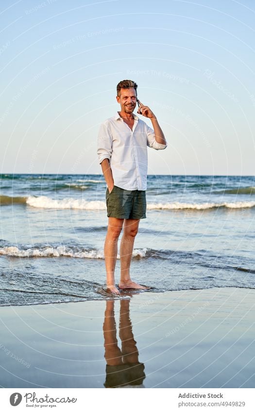 Geschäftsmann, der am Meer spazieren geht und mit seinem Smartphone spricht Spaziergang Mann Lächeln MEER benutzend reden Urlaub Strand Sommer Telefonanruf