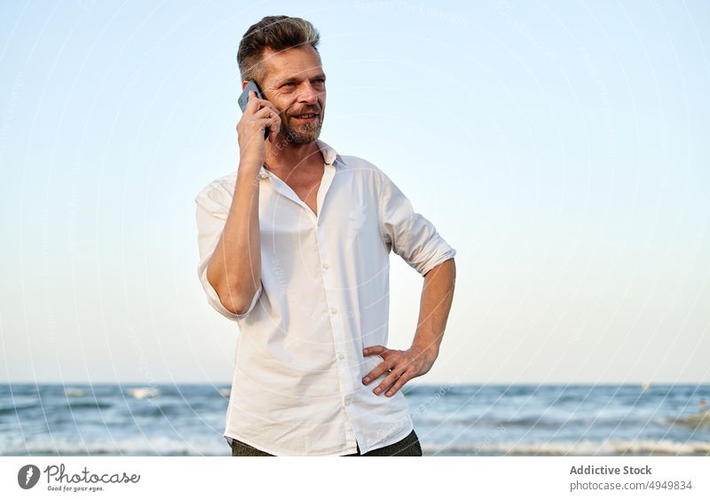 Geschäftsmann, der am Meer spazieren geht und mit seinem Smartphone spricht Spaziergang Mann Lächeln MEER benutzend reden Urlaub Strand Sommer Telefonanruf