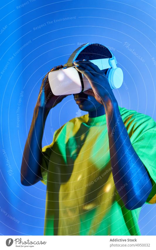 Junger afroamerikanischer Mann sieht Video in VR-Brille Virtuelle Realität zuschauen Konzentration eintauchen Erfahrung erkunden futuristisch Cyberspace