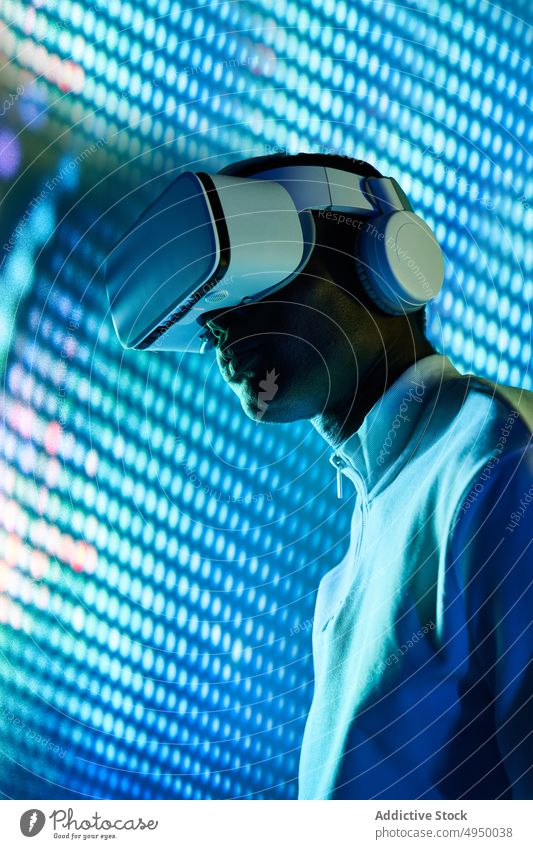 Ernster schwarzer Mann, der einen großen Bildschirm berührt, während er die virtuelle Realität mit einem modernen Headset erkundet Virtuelle Realität erkunden