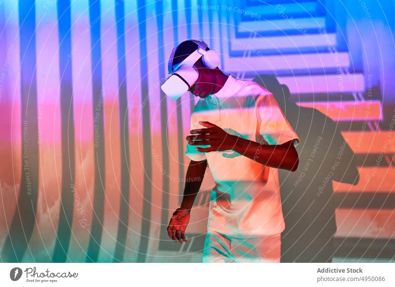 Schwarzer Mann, der ein imaginäres Objekt betrachtet, während er mit einer VR-Brille den Cyberspace erkundet Virtuelle Realität Tanzen Simulator Erfahrung
