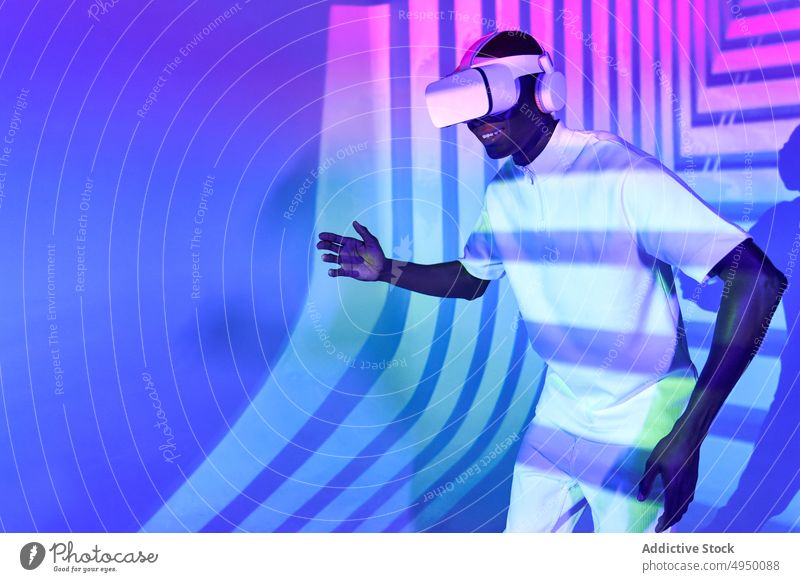 Schwarzer Mann, der ein imaginäres Objekt betrachtet, während er mit einer VR-Brille den Cyberspace erkundet Virtuelle Realität Tanzen Simulator Erfahrung