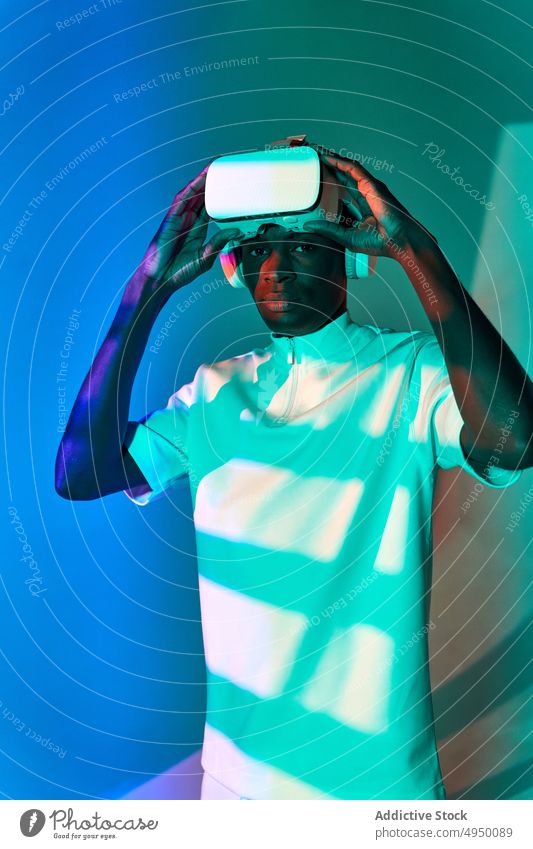 Cooler junger Afroamerikaner passt VR-Brille im Studio an Mann Virtuelle Realität Schutzbrille Abheben Erfahrung futuristisch ernst Porträt Innovation digital