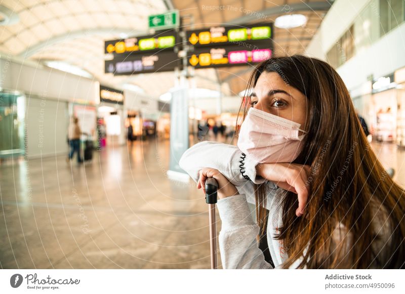 Gelangweilte Frau, die im Flughafen auf ihren Flug wartet Terminal reisen Tourist warten fettarm Koffer Seuche gelangweilt jung brünett Gesichtsmaske Passagier