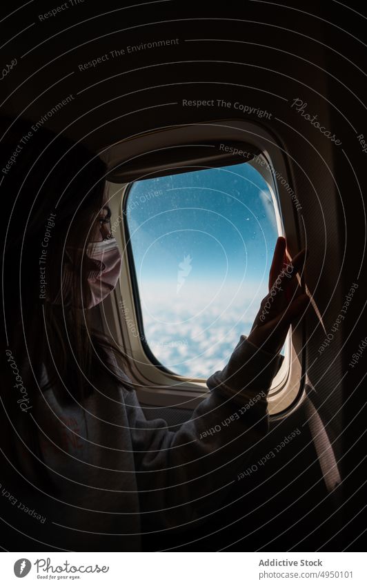 Weiblicher Reisender schaut aus dem Fenster Frau Ebene Blauer Himmel wolkig dunkel Kabine Urlaub Pandemie Passagier COVID19 Fluggerät neue Normale bewundern