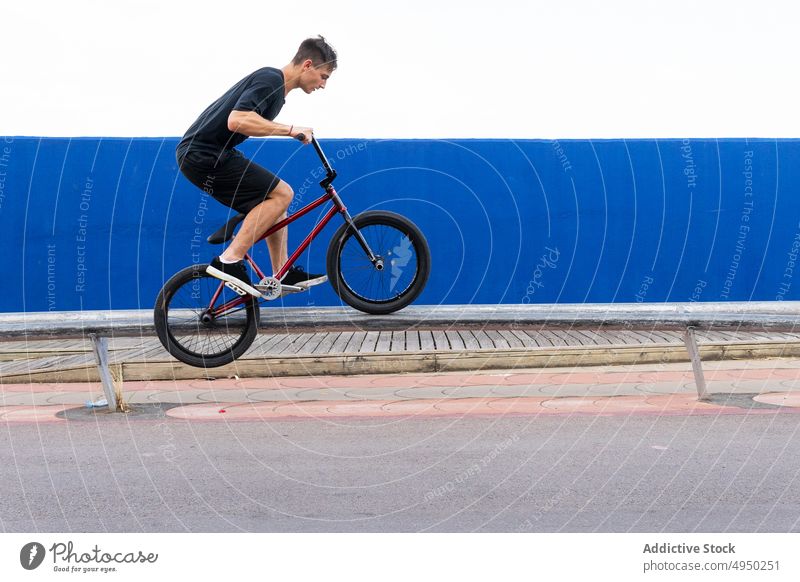Mann macht Sprungtrick auf BMX-Rad springen Fahrrad bmx Trick Wand Straße Wochenende Sommer Aktivität männlich Energie urban Stunt lässig Radfahrer Zeitgenosse