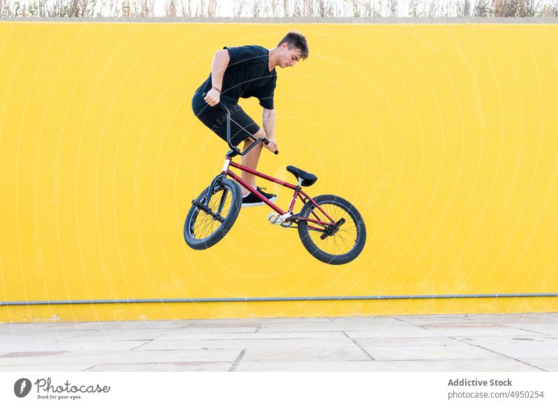 Mann macht Sprungtrick auf BMX-Rad springen Fahrrad bmx Trick Wand Straße Wochenende Sommer Aktivität männlich Energie urban Stunt lässig Radfahrer Zeitgenosse