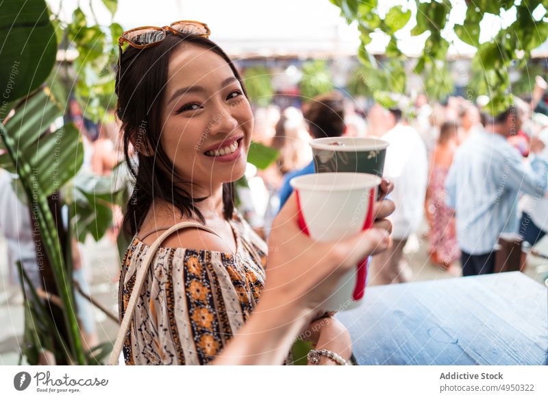 Glückliche asiatische Frau, die einem Freund einen Toast ausspricht Klirren Pappbecher Erfrischungsgetränk Restaurant Zuprosten Lächeln Wochenende Straße
