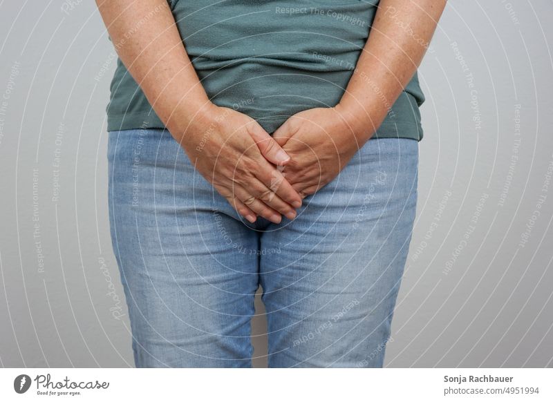 Eine Frau hält ihre Hände vor dem Unterleib blasenentzündung Schmerz Gesundheit Bauch Körper Krankheit Jeanshose 50 plus Tabu gynäkologisch
