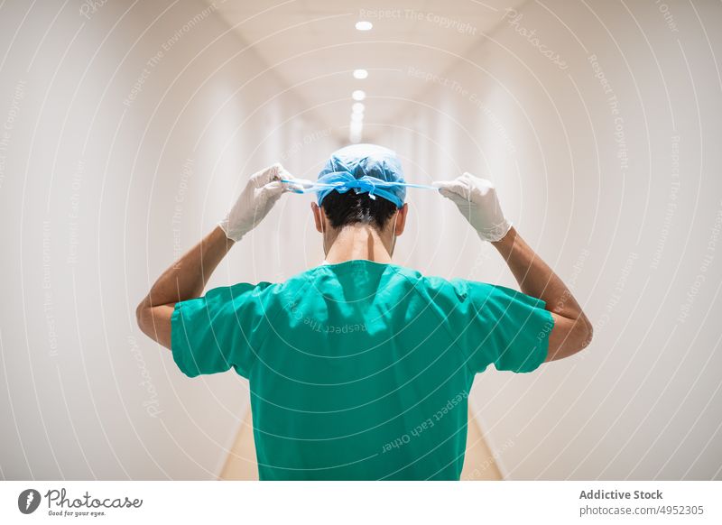 Anonymer Chirurg bindet medizinische Mütze im Klinikflur Kopplungsbindung Verschlussdeckel Uniform vorbereiten professionell Mann Krankenhaus Gang Arbeit