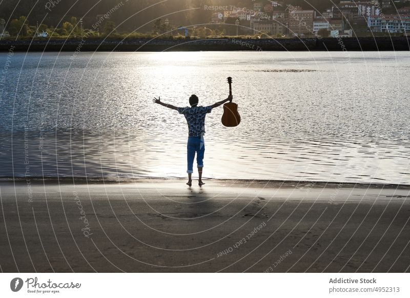 Unbeschwerter männlicher Musiker mit Gitarre am Meeresufer Mann Strand sorgenfrei Freiheit MEER Sommer genießen Gitarrenspieler akustisch nass ausdehnen Ufer
