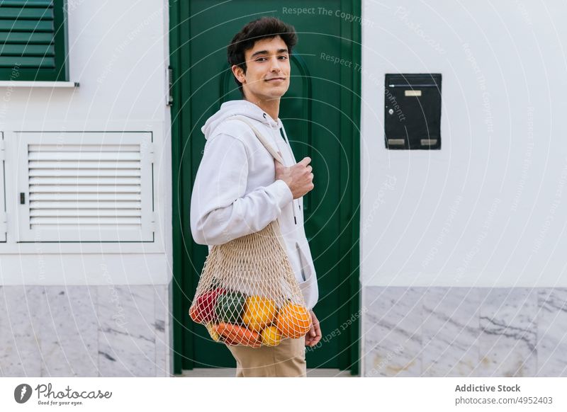 Mann mit Obst im Netzbeutel in der Stadt ineinander greifen Tasche umweltfreundlich Frucht Straße Lebensmittelgeschäft Öko natürlich keine Verschwendung