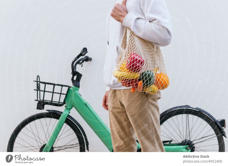 Crop-Mann mit Netztasche in der Nähe von Fahrrädern in der Stadt Lebensmittelgeschäft ineinander greifen Tasche umweltfreundlich keine Verschwendung Straße