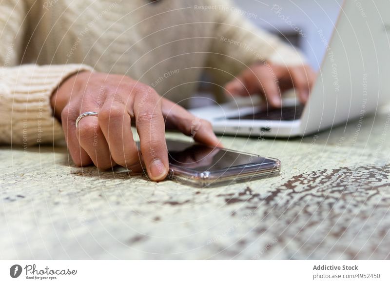 Unkenntlich gemachter Mann, der mit Netbook und Smartphone aus der Ferne arbeitet Tippen Laptop benutzend abgelegen freiberuflich Arbeit online Beruf