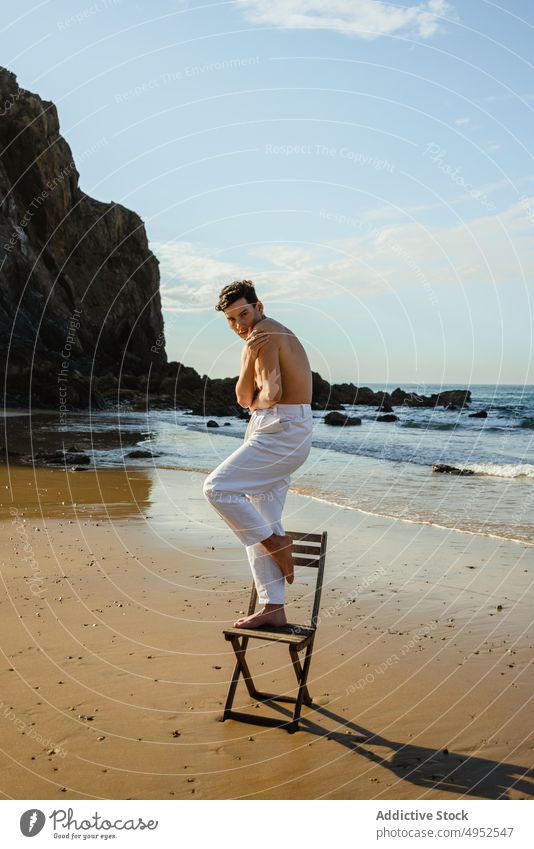 Mann ohne Hemd steht auf einem Stuhl am Meer Strand MEER Stil stehen Gleichgewicht Konzept verwundbar Umarmen männlich Model jung Barfuß Küste Ufer Sommer