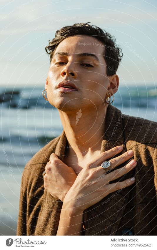 Stilvolles androgynes Männchen gegen das Meer Mann MEER Vorschein berühren Jacke Natur Porträt Mode männlich Model jung ethnisch Kleidungsstück trendy