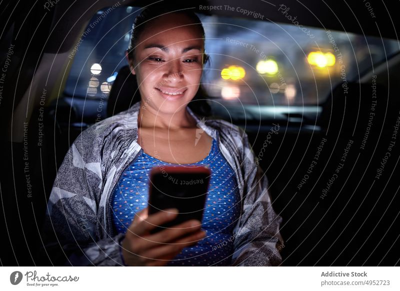 Frau benutzt Smartphone im Auto PKW Passagier benutzend Browsen Großstadt Nacht Automobil dunkel Mobile Telefon Funktelefon Surfen Internet Nachricht urban