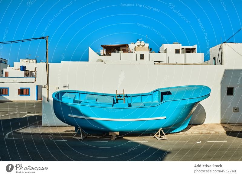 Blaues Boot auf der Straße in der Nähe von Gebäuden im Sonnenlicht Architektur nautisch Verkehr Blauer Himmel Insel Maure Einsamkeit hell Schatten Asphalt