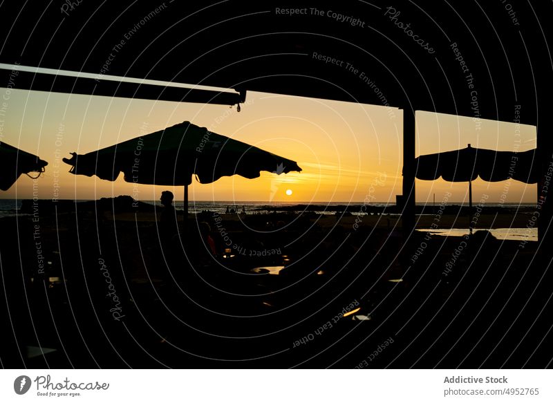 Unkenntlich Reisende Silhouette unter Sonnenschirm gegen Meer in der Nacht Reisender MEER Sonnenuntergang Natur Landschaft Himmel Ufer Horizont Mann reisen