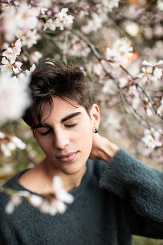 Junger Mann mit geschlossenen Augen unter blühendem Baum Natur im Freien Model Park Blume Mandel Blütezeit Unschärfe Botanik Ast Windstille elegant Umwelt