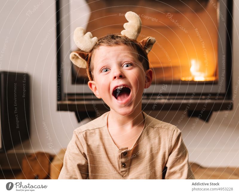 Erstaunter Junge mit Rentiergeweih am Kamin Kind Schock Geweih Stirnband omg Weihnachten Feuerstelle Feiertag erstaunt Erstaunen atemberaubend Wohnzimmer