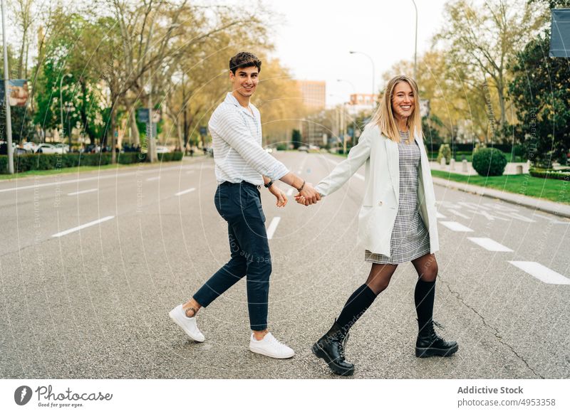Fröhliches Paar beim Überqueren der Straße in der Stadt Händchenhalten Spaziergang schlendern durchkreuzen Großstadt Liebe Zusammensein Partnerschaft urban Stil