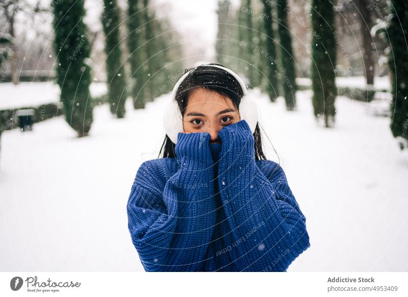 Asiatische Millennial-Frau in Strickwaren im Winterpark Deckblatt schüchtern Schneefall sanft Park kalt Porträt Wetter Winterzeit idyllisch urban Angebot Stil