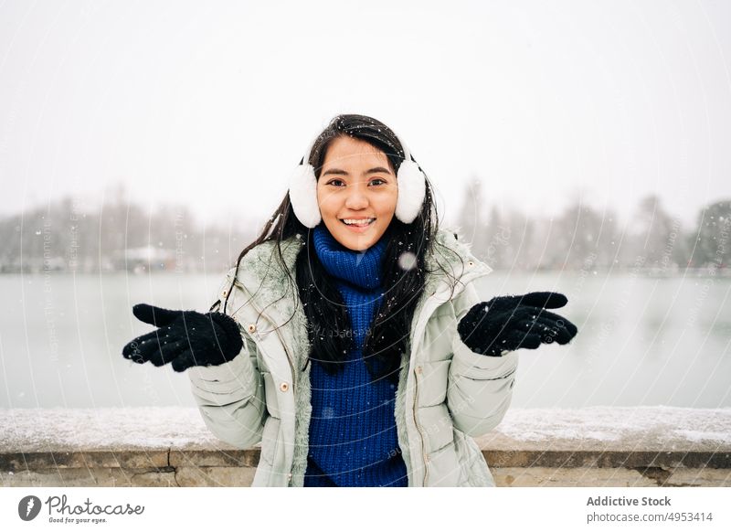 Asiatische Frau fängt Schneeflocken in der Nähe des Sees im Winter fangen bewundern Winterzeit Fluss idyllisch Stauanlage urban Porträt Zaun alt Stil