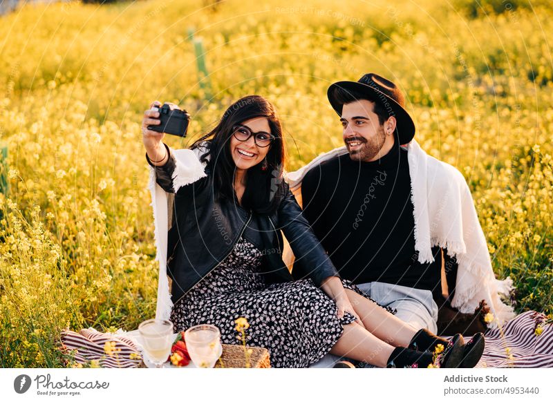 Glückliches ethnisches Paar nimmt Selfie auf Fotokamera im Feld Fotoapparat Gedächtnis Moment romantisch Partnerschaft Wiese benutzend Gerät Selbstportrait