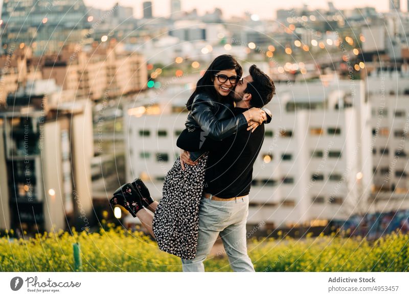 Ethnischer Mann küsst glückliche Freundin in der Stadt Paar Kuss Umarmen anheben Porträt Partnerschaft amour romantisch Glück Vergnügen Liebe Seelenverwandter