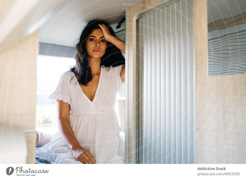 Hispanische Frau sitzt auf dem Bett im Van reisen Kleintransporter Wohnmobil Reisender Gelassenheit Wohnwagen ruhig Ausflug ethnisch hispanisch Komfort