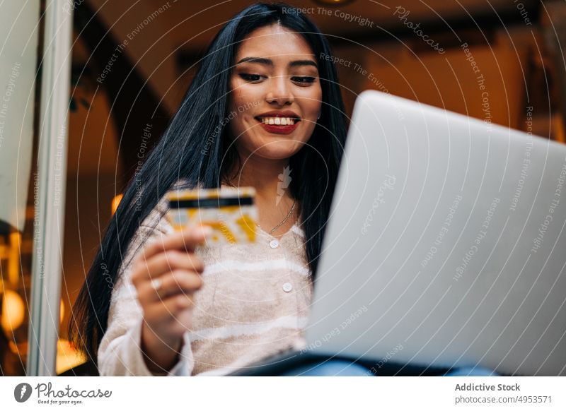 Lächelnder asiatischer Einkäufer mit Laptop und Kreditkarte Käufer kaufen online heiter Zahlung e-Commerce Frau benutzend Apparatur Gerät feminin angenehm