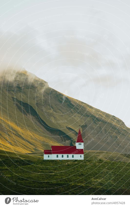Landschaftstapete der Kirche von Vík í Mýrdal in Island vor einem massiven Berg während des Sonnenuntergangs. Kopieren Sie Raum Bild, stimmungsvollen Stil. Besuchen Sie Island, Reise-Route auf Ödland