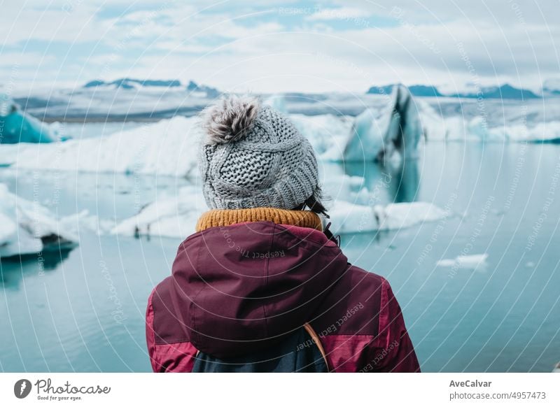 Traveler Frau in kaltem Wetter Kleidung vor den Gletschern von Jökulsárlón in Island während einer stimmungsvollen Tag mit Wasser gefüllt. Lebe deinen Traum, Liebe in Island, Roadtrip-Stil.copy space