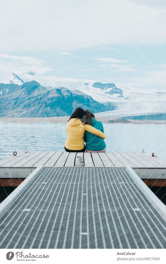 Paar junge Frau Reisende zurück Schuss sitzen auf den Docks entspannen und denken, vor den Gletschern von Jökulsárlón in Island. Platz kopieren. Lebe deinen Traum, Liebe in Island, Roadtrip-Stil