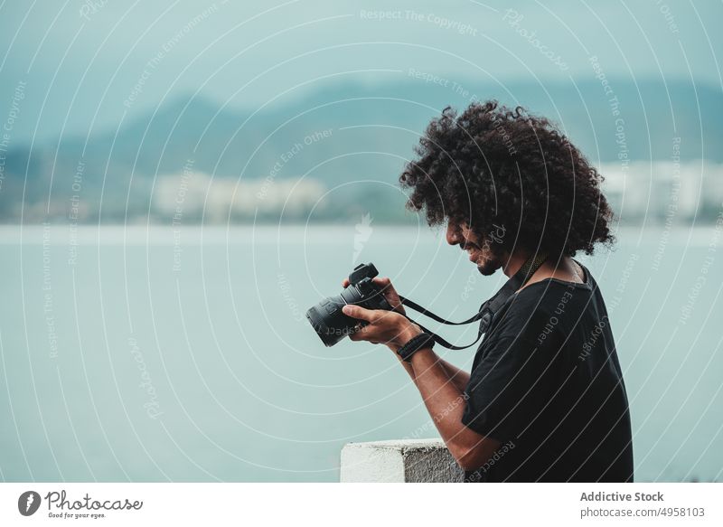 Schwarzer Fotograf, der das Meer mit einer professionellen Kamera fotografiert fotografieren Fotoapparat Fokus digital Gedächtnis Mann benutzend Gerät Moment